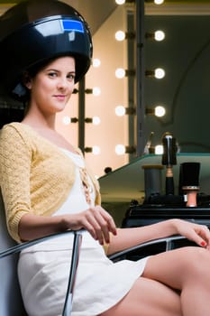Portrait of a young woman sitting under hair dryer