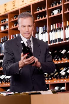 Businessman reading the label on a wine bottle