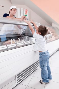 Sales clerk giving ice cream to a boy in an ice cream parlor