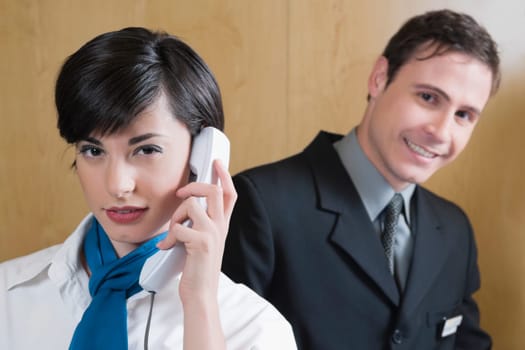 Close_up of a receptionist talking on the telephone and a businessman standing behind her