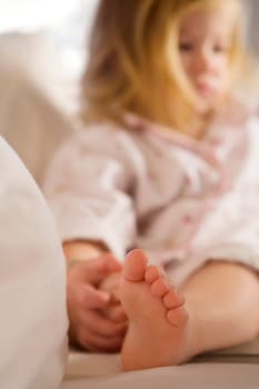 Close_up of a baby girl sitting on the bed