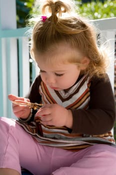 Close_up of a baby girl holding an insect