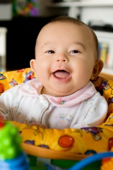 Portrait of a baby girl sitting in a toy swing and smiling