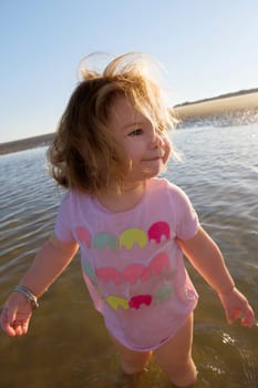 Close_up of a baby girl standing in water and looking away