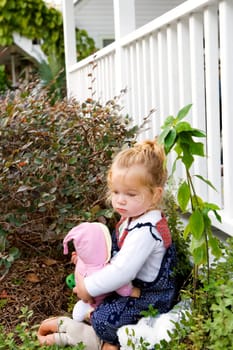 Side profile of a baby girl holding a doll and looking serious
