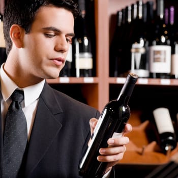 Businessman reading the label on a wine bottle