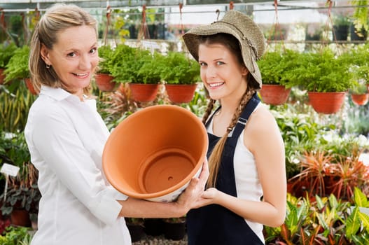 Female planter giving pot to customer in a greenhouse