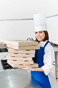 Female chef holding stack of pizza boxes and smiling