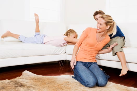 Woman playing with her son and a daughter in a living room