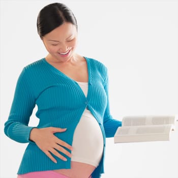 Pregnant woman touching her abdomen and holding a book