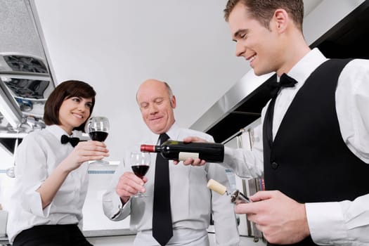 Waiter pouring wine into the glasses of his colleagues