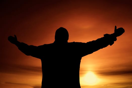 Silhouette of a person standing with arms raised