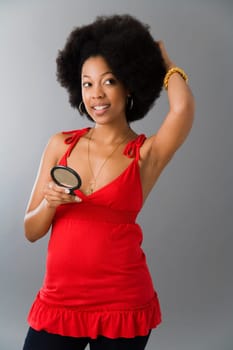 Young woman holding a hand mirror and looking sideways