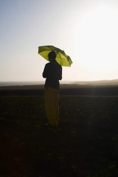 Farmer holding an umbrella in the field, California, USA