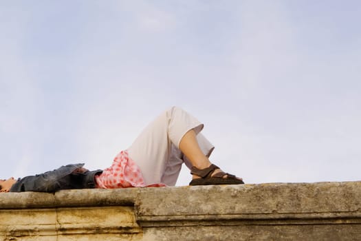 Low angle view of a young woman lying on a stone wall