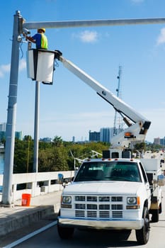Low angle view of a maintenance engineer on a mobile crane repairing a security camera on a pole