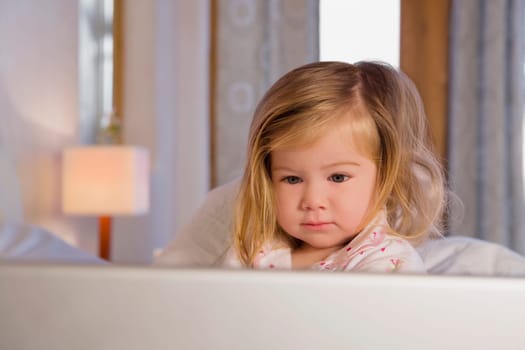 Close_up of a baby girl looking at a laptop