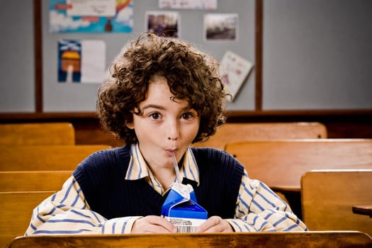 Schoolboy drinking juice in a classroom
