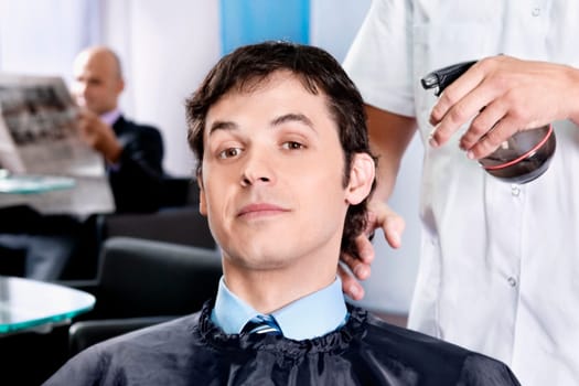 Barber spraying water on a manŽs hair