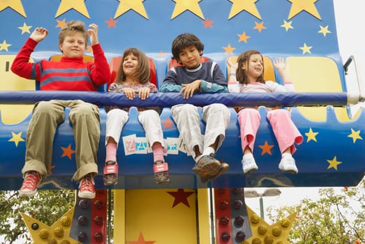 Low angle view of boys and girls on an amusement park ride