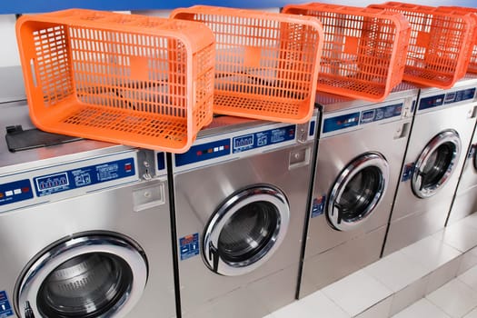 Laundry baskets on washing machines in a laundromat