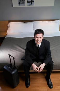 Portrait of a businessman sitting on the bed with his luggage