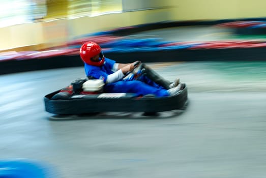 Side profile of a person go_carting on a motor racing track