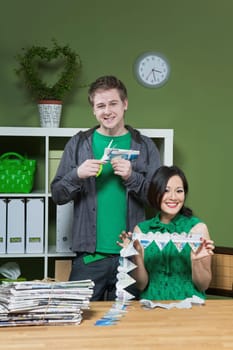 Woman holding a paper chain and a man cutting a paper