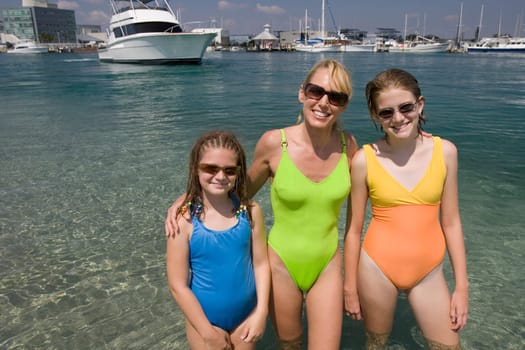 Mature woman with her daughters standing in the sea and smiling