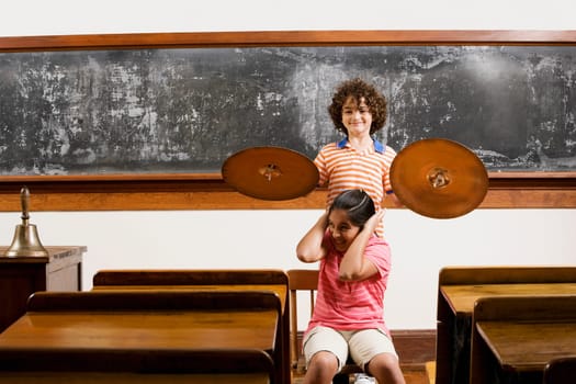 Two students having fun with cymbal in a classroom