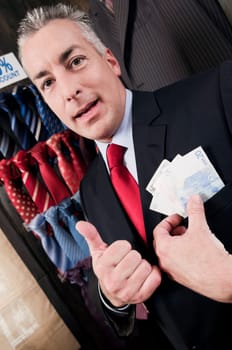Businessman holding currency note in a clothing store