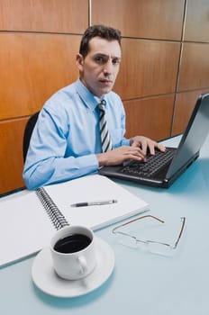 Portrait of a businessman working on a laptop in an office