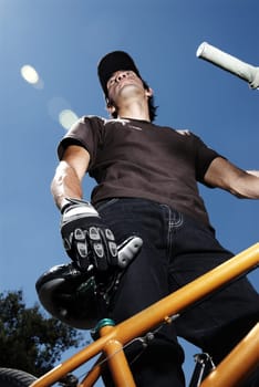 Low angle view of a young man standing with a mountain bike