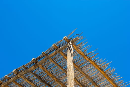 Low angle view of a thatched roof against the blue sky