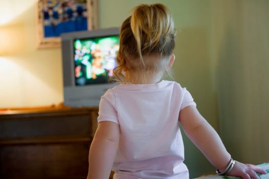 Rear view of a baby girl watching television