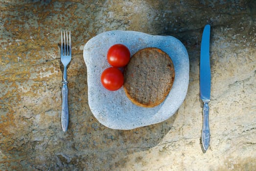 Close_up of two tomatoes with a bread on a stone