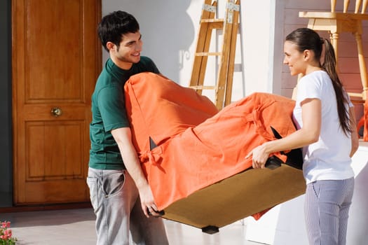 Side profile of a young couple carrying an armchair