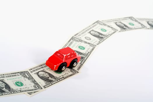 Toy car moving on a US paper currency road