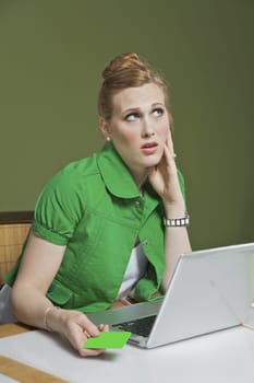 Businesswoman holding a credit card and thinking in the office