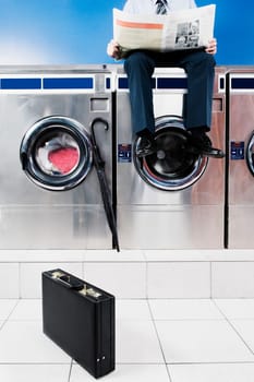 Businessman reading a newspaper in a laundromat