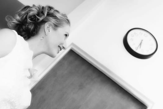 Side profile of a mid adult woman looking at a clock and smiling