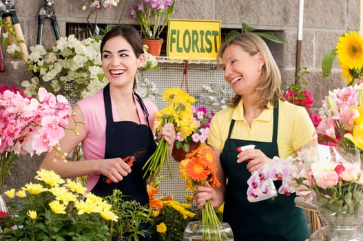 Two female florists working in a flower shop and smiling