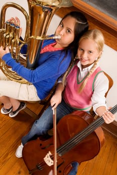 Portrait of two girls playing violin and tuba in a class