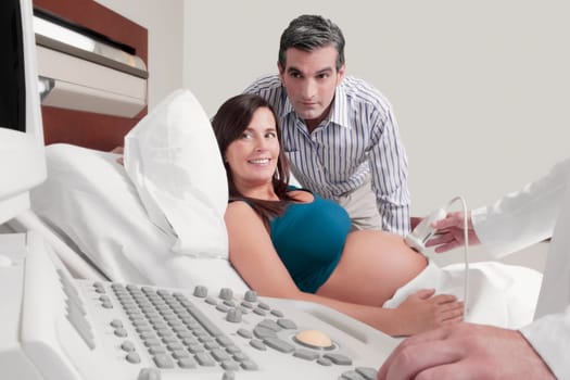 Pregnant woman going through an ultrasound scan with her husband beside her