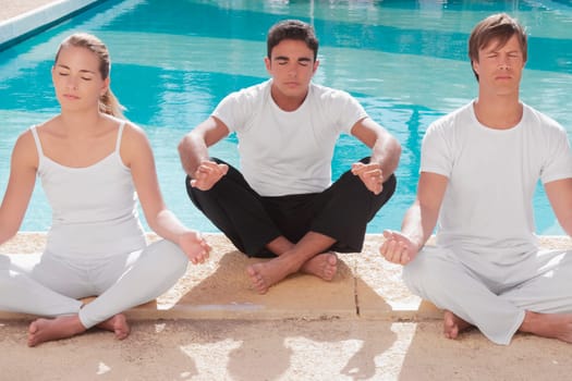 Three friends practicing yoga at the poolside