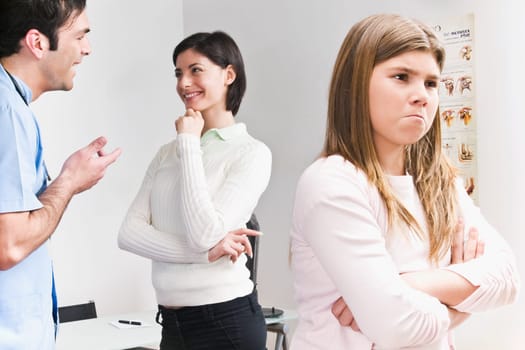Girl looking upset from her mother and doctor