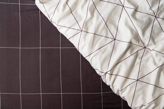 Elegant linen plaid sheet and white blanket with geometric design.