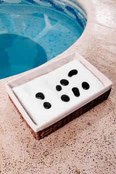 Towel and pebbles in a basket beside a hot tub