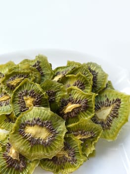 Dehydrated kiwi slices with sugar isolated on white plate.