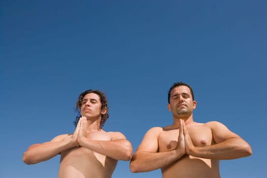 Low angle view of two men meditating